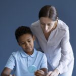 Speech therapist assisting a young boy with colorful educational therapy tools.