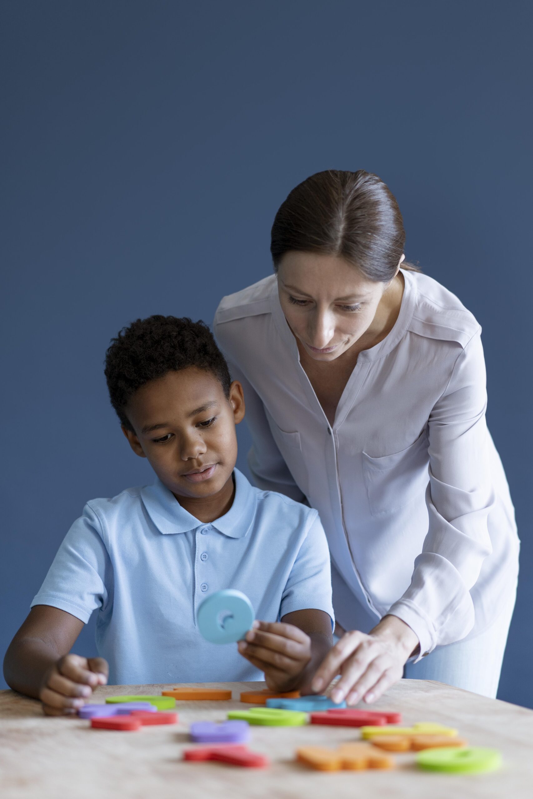 Speech therapist assisting a young boy with colorful educational therapy tools.